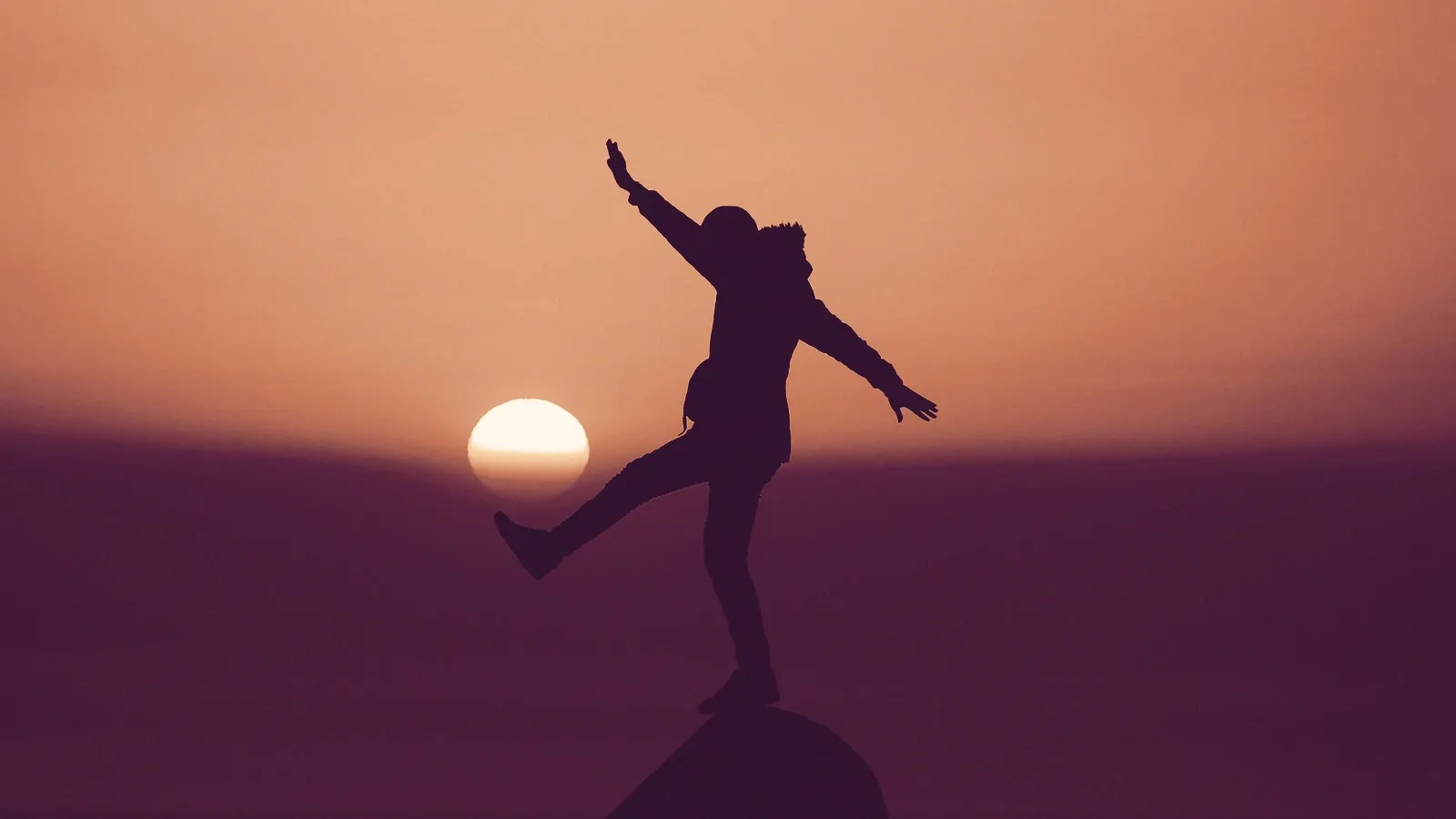Persona in equilibrio su una roccia al tramonto